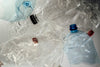 Bouteilles d'eau en plastique vides et écrasées sur fond blanc, impacts de l'eau en bouteille au quotidien