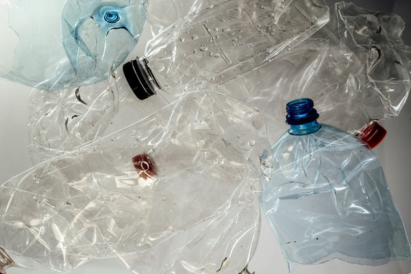 Bouteilles d'eau en plastique vides et écrasées sur fond blanc, impacts de l'eau en bouteille au quotidien