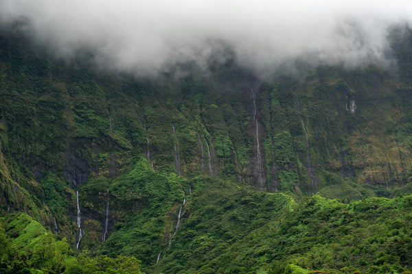 Falaises couvertes de végétation tropicale et de cascades sous les nuages, saison cyclonique en Polynésie